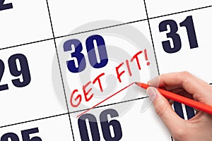 30th day of the month. Hand writing text GET FIT and drawing a line on calendar date. Save the date.