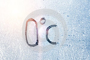 32 degrees Fahrenheit or 0 Celsius number lettering on icy glass covered with ice and frost. The concept of extreme cold weather