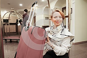 A 35-40 year old woman checks into a hotel. Blonde at the troll to transport suitcases and luggage. In summer clothes