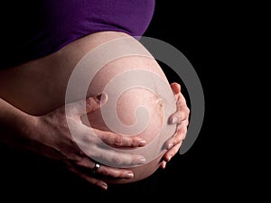 36 weeks pregnant young woman holding her naked belly