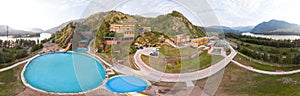 360-degree panorama from the air to a tourist recreation center in the Altai mountains with hotel buildings and pools on a warm