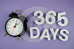 365 Days alphabet letters with alarm clock top view on purple background, business and education concept background