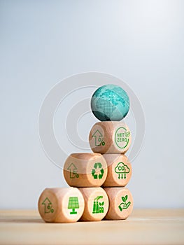 3d earth on wood cube stack as a graph with words Net Zero and green renewable energy icons.