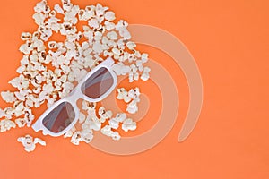 3d glasses and popcorn are isolated on a orange background. Flat lay. Copyspace