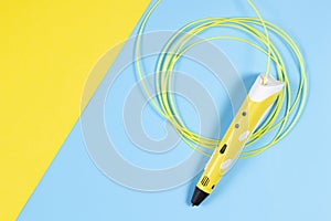 3d pen with colourful plastic filament on blue and yellow background.