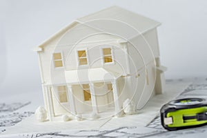 3D plastic model of the family house printed on a 3D printer for architectural use and measuring tape in foreground.