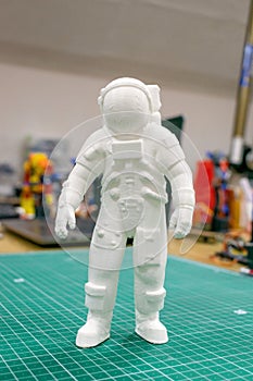 3D printed astronaut, cosmonaut, robot on the background of devices and laptop. Spaceman model printed on automatic three