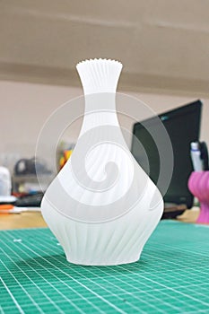 3D printed object vase on the background of laptop. Model printed on automatic three dimensional 3d printer