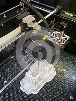3D printer in action, printing of a complex white buliding model in progress, new technology, closeup