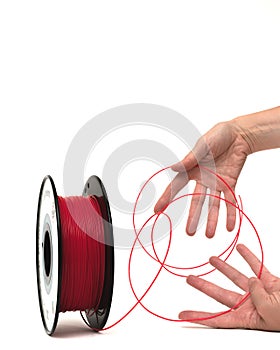 3D Printer Plastic Filament. Spool of red thermoplastic wire in hands.