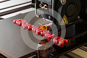 3D printer printing words with red plastic