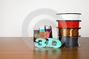 3D printing filament reels with text `3d` and a simbol of heart on wooden background