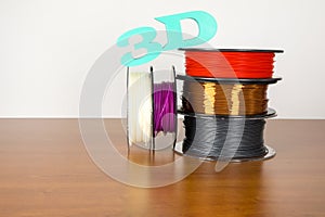 3D printing filament reels with text `3d` on wooden background