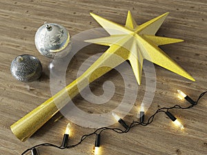 3d render of a gold decoration star and Christmas decoration baubles with black lights on a wooden background