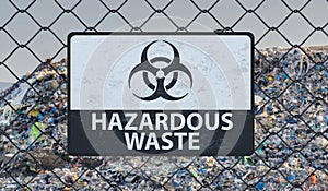 3D rendered illustration of hazardous waste sign on chain link fence. Landfill in background