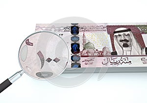3D Rendered new Saudi Arabia money with magnifier investigate currency isolated on white background