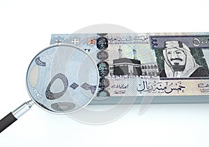 3D Rendered Saudi Arabia money with magnifier investigate currency on white background