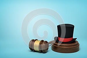 3d rendering of black top hat with red ribbon on sounding block with judge gavel lying beside on light-blue background.