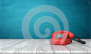 3d rendering of a bright red dial phone standing on a wooden desk and a blue wall background.