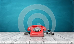 3d rendering of a bright red dial phone standing on a wooden desk and a blue wall background.