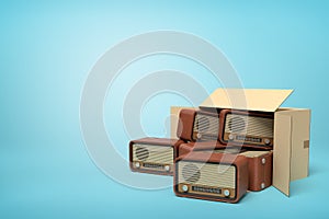 3d rendering of cardboard box lying sidelong full of old-fashioned radios on light-blue background.