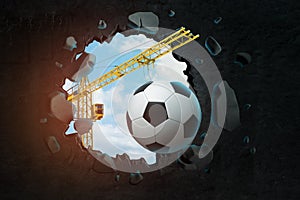 3d rendering of construction crane and football ball breaking black wall