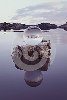 3d rendering of crystal ball on river rock in the evening sunlight