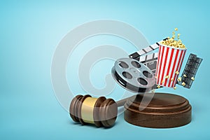 3d rendering of film reel, popcorn bucket, and clapperboard suspended in air above sound block with gavel beside on blue