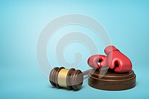 3d rendering of red boxing gloves on round wooden block and brown wooden gavel on blue background