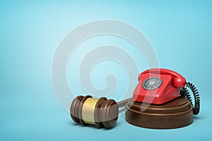 3d rendering of red retro telephone standing on sounding block with gavel beside on light-blue background with copy