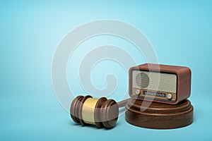 3d rendering of retro radio set on sounding block with brown gavel lying beside on light-blue background with copy space