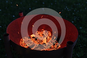 3d rendering of rusty fire bowl grill filled with glowing charcoals at night