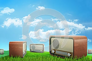 3d rendering of several brown retro radio sets on green sunlit meadow under blue sky with white clouds.