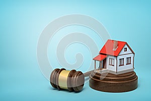 3d rendering of small white house with red roof on round wooden block and brown wooden gavel on blue background