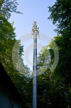 3G, 4G, LTE Telecommunication mast and green trees at the blue sky