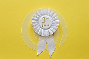 3rd place white ribbon rosette on yellow