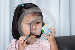 4-5 years happy child hold a globe and a magnifying glass in hands.