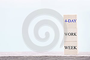 4 day working week words on wooden cube on blue background. reducing burnout and stress levels concept.