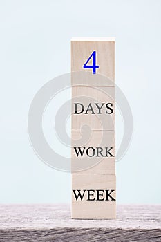 4 day working week words on wooden cube on blue background. reducing burnout and stress levels concept.
