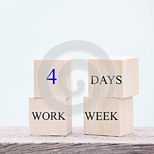 4 day working week words on wooden cube on blue background. reducing burnout and stress levels concept.