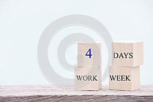 4 day working week words on wooden cube on blue background. reducing burnout and stress levels concept.