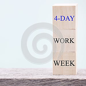 4 day working week words on wooden cube on blue background. reducing burnout and stress levels concept.
