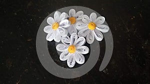 4 easy flowers made from pieces of white paper then rolled using the paper quilling art technique