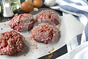 4 meat burgers, pork round cutlets with spices on a black background, eggs, schnitzel