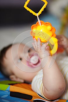 4-Month-Old Baby girl playing with toys. Girl pulling hand for a toy. The kid plays the rattle