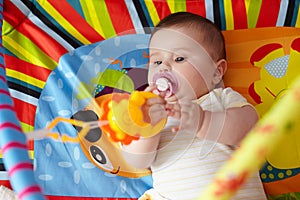 4-Month-Old Baby girl playing with toys. Girl pulling hand for a toy. The kid plays the rattle