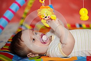 4-Month-Old Baby girl playing with toys. Girl pulling hand for a toy. The kid plays the rattle
