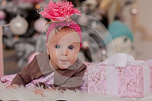 4 month old little girl under the Christmas tree. baby girl with gifts under Christmas tree