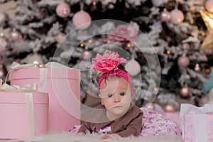 4 month old little girl under the Christmas tree. baby girl with gifts under Christmas tree