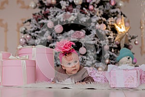 4 month old little girl under the Christmas tree. baby girl with gifts under Christmas tree